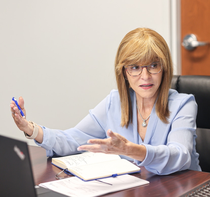 Professional woman discussing commercialization patient support and reimbursement services, with a notebook and pen in hand.