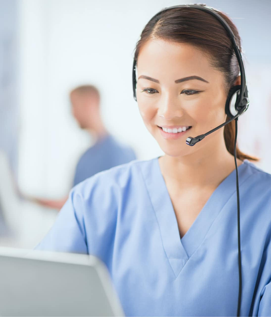 Asian nurse with a headset, engaging in patient outreach and support programs while working on a laptop.