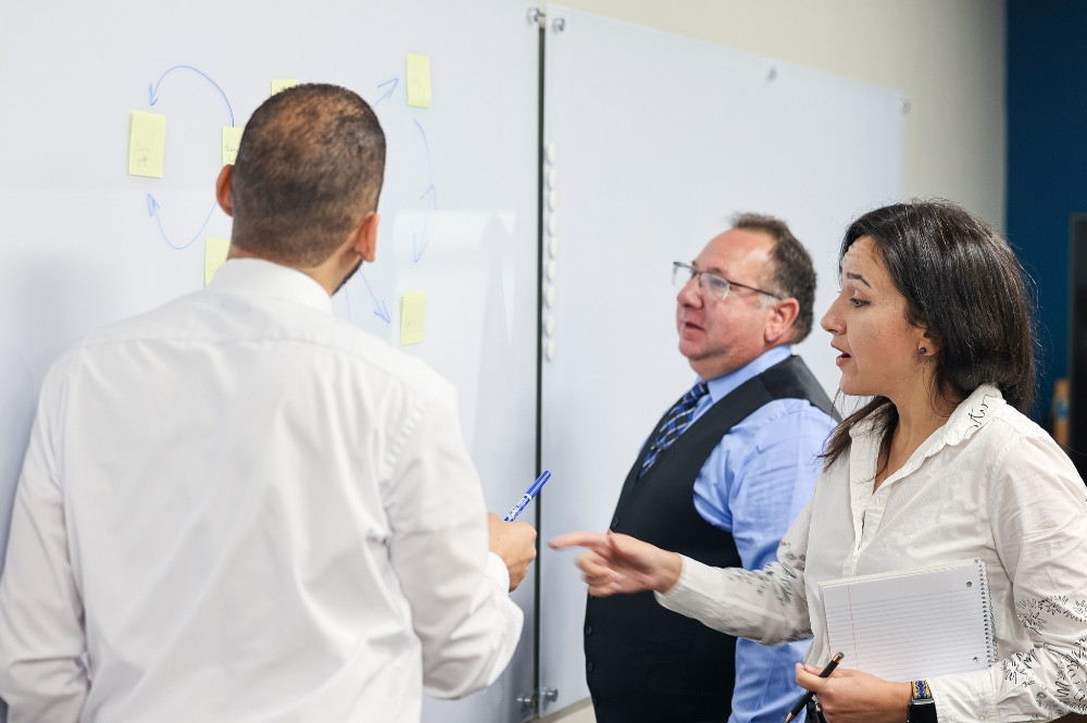 Clinical trial team discussing patient concierge logistics and support at a whiteboard