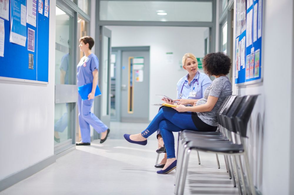 Clinical research coordinator speaking with a clinical trial participant in a modern clinic hallway to improve patient engagement and retention.