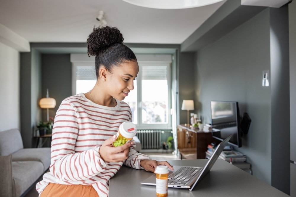 Participant using laptop and medication at home for decentralized clinical trial support