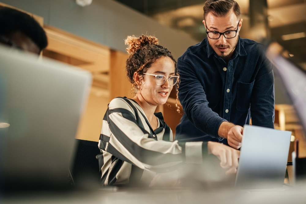 Technology project coordinator in clinical trials reviewing healthcare systems with a colleague