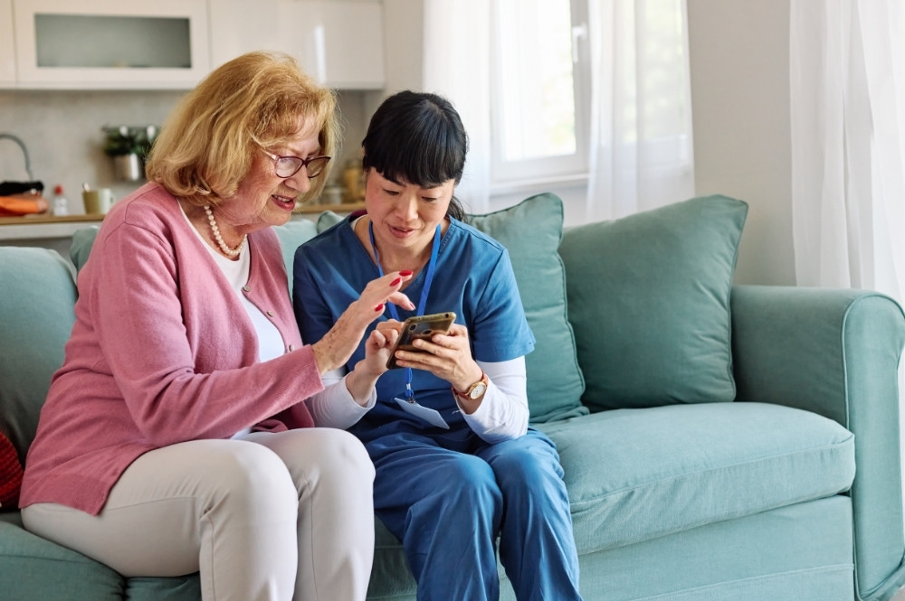 Nurse helping patient use mobile phone for pharma hub services and patient support
