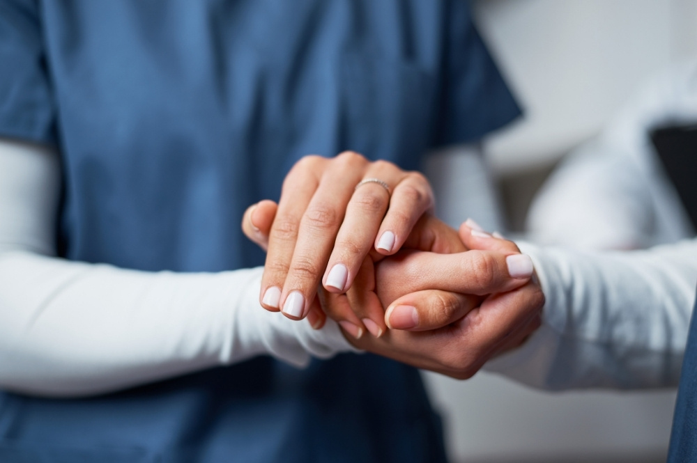 Healthcare professional holding a patient’s hand to represent rare disease clinical trial support